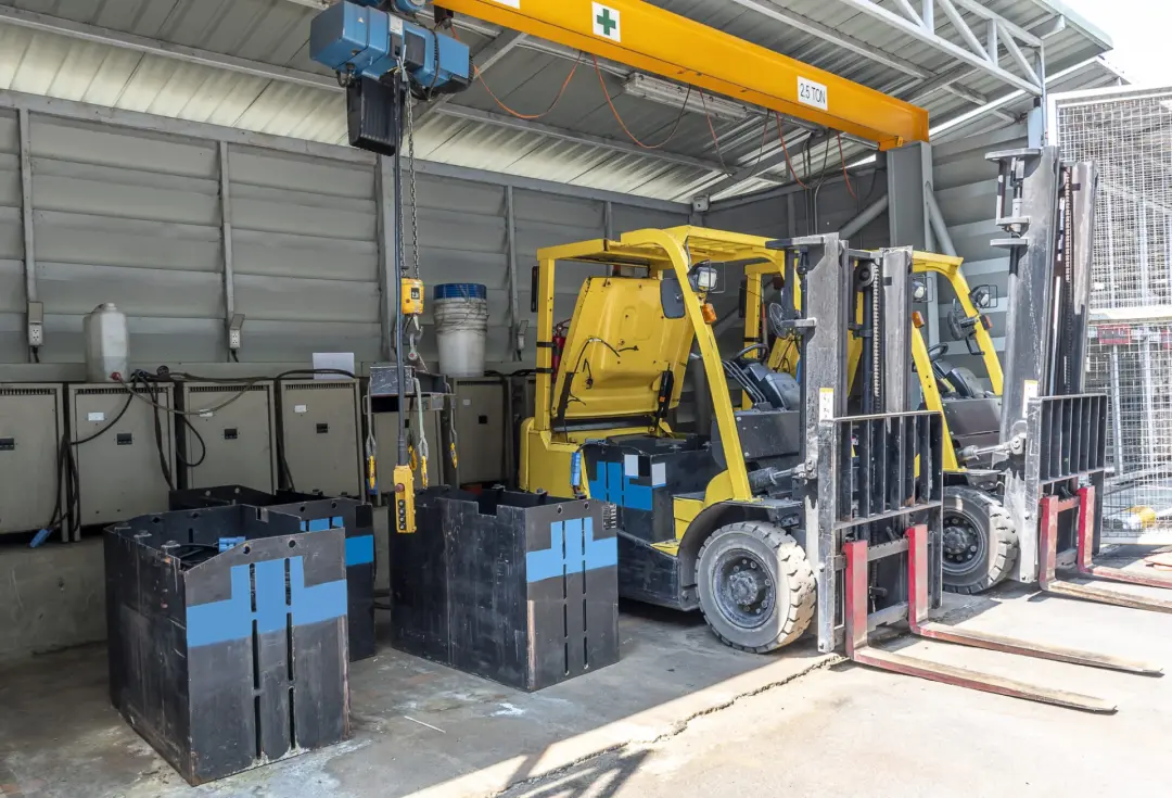 Electric forklifts parked in a battery charging bay
