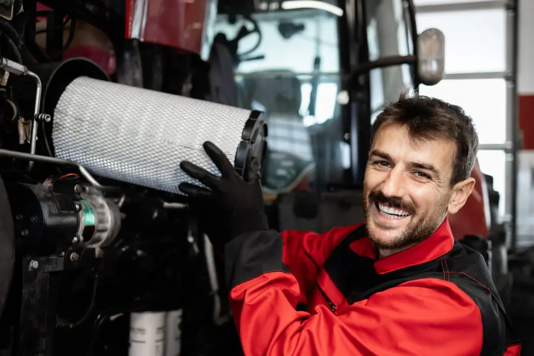 Engineer in red workwear changing a large air filter during a service