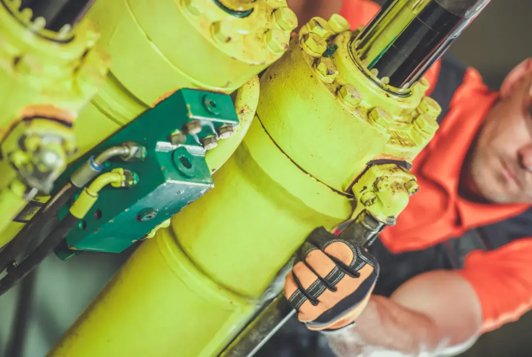 Engineer with a spanner repairing a hydraulic cylinder