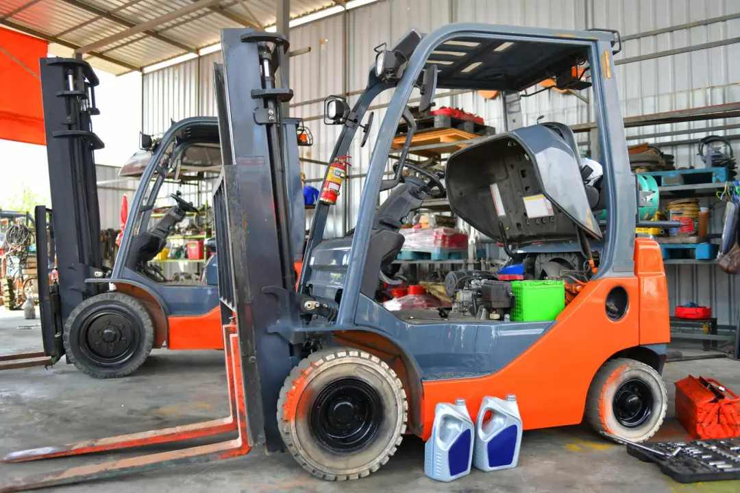 Forklift with its engine cover raised in a repair workshop